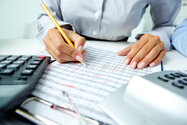 Mujer generando informe en un escritorio con dos calculadoras